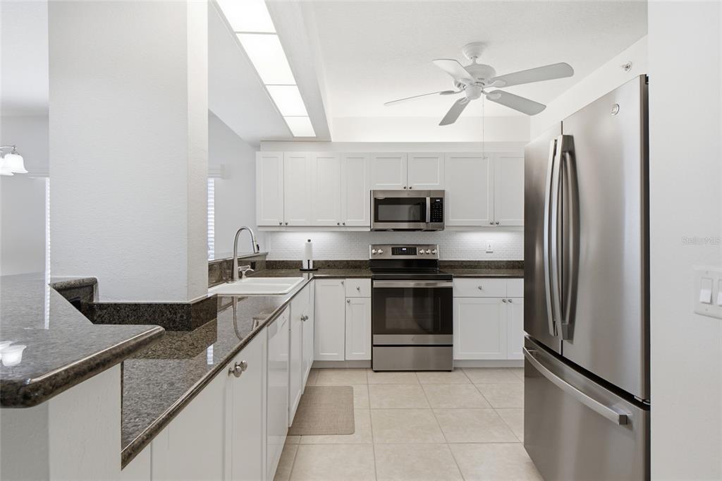 A kitchen with white cabinets, granite countertops, stainless steel appliances, and a view of water — 418 LAUREL LAKE DRIVE UNIT 106, VENICE, FL