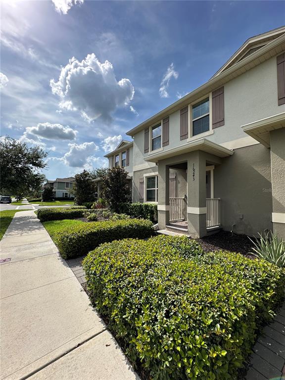 A two-story townhouse exterior features a beige facade, brown shutters, and a landscaped front yard — 16237 QUIET VISTA DRIVE, WINTER GARDEN, FL