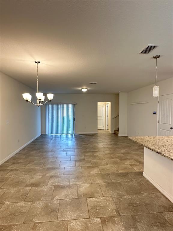 An open-concept room features tile flooring, a dining chandelier, and sliding glass patio doors — 16237 QUIET VISTA DRIVE, WINTER GARDEN, FL