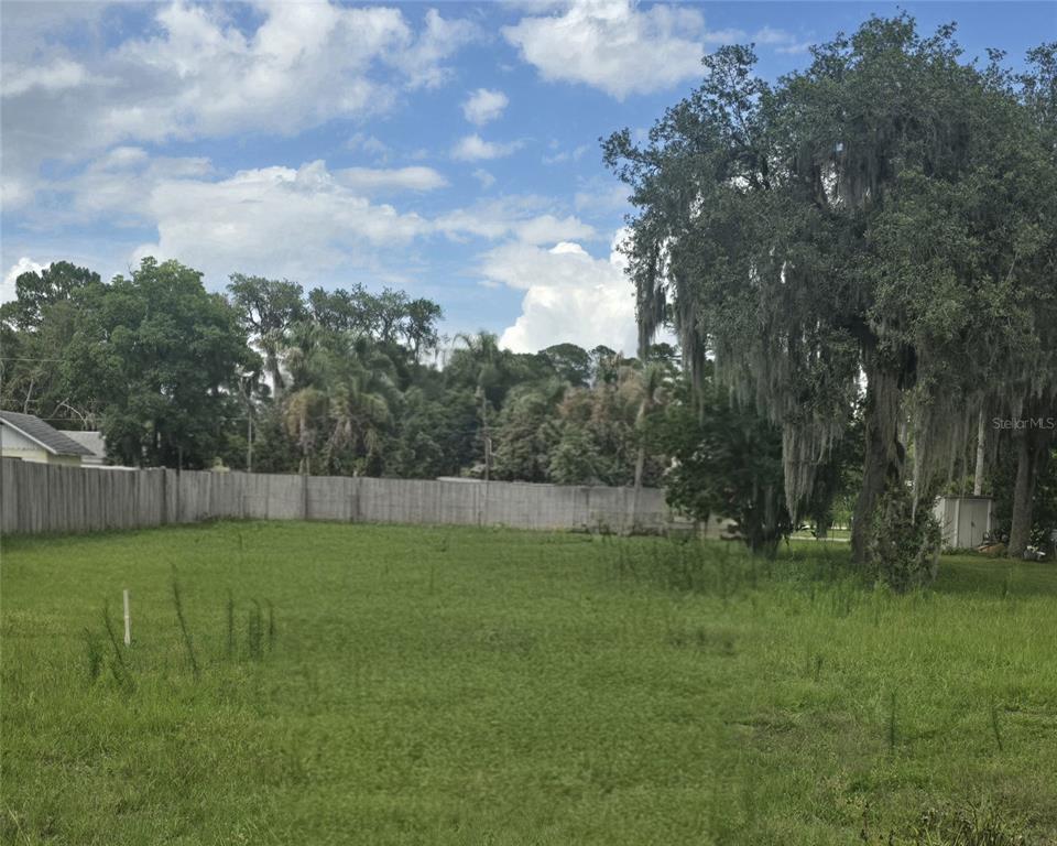 A grassy, vacant lot is enclosed by a wooden fence with large trees nearby — 276 LUIS LANE, DEBARY, FL