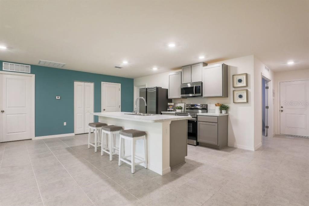 A kitchen features a white island with bar stools, gray cabinetry, and a teal accent wall — 276 LUIS LANE, DEBARY, FL