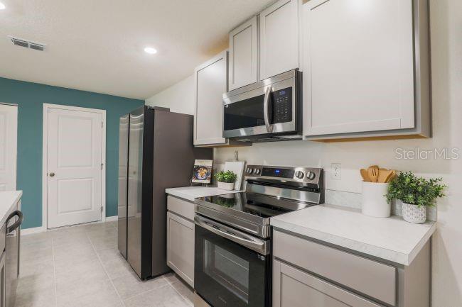 A kitchen features grey cabinets, stainless steel appliances, white countertops, and a teal accent wall — 276 LUIS LANE, DEBARY, FL