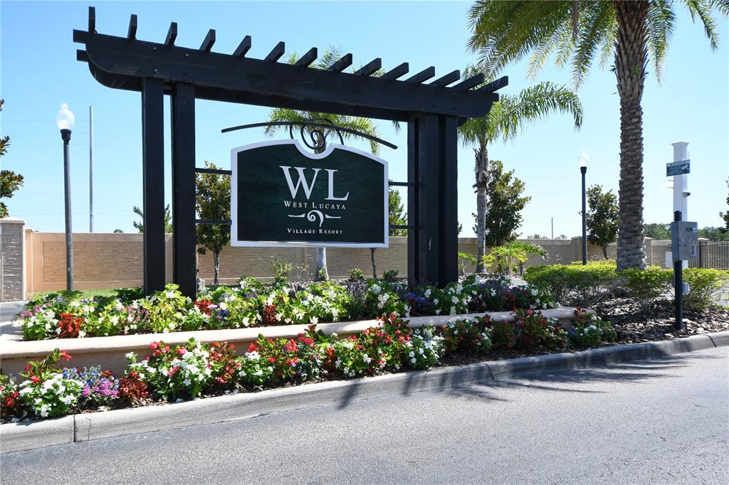 A black wooden sign for West Lucaya Village Resort stands behind a bed of flowers — 8927 SHINE DRIVE, KISSIMMEE, FL