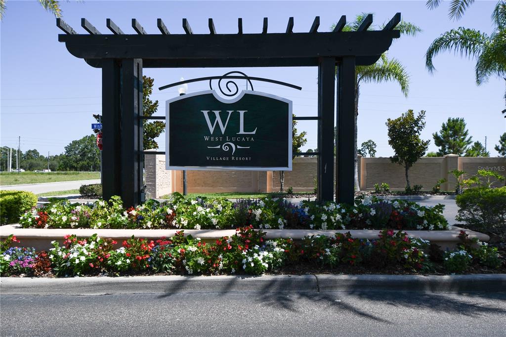 A wooden pergola structure displays the West Lucaya Village Resort sign above a flower bed — 8927 SHINE DRIVE, KISSIMMEE, FL