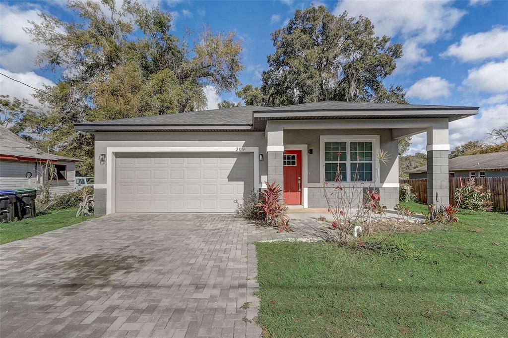 A single-story house with a gray exterior, a red front door, and a paved driveway — 309 E 13TH STREET, APOPKA, FL