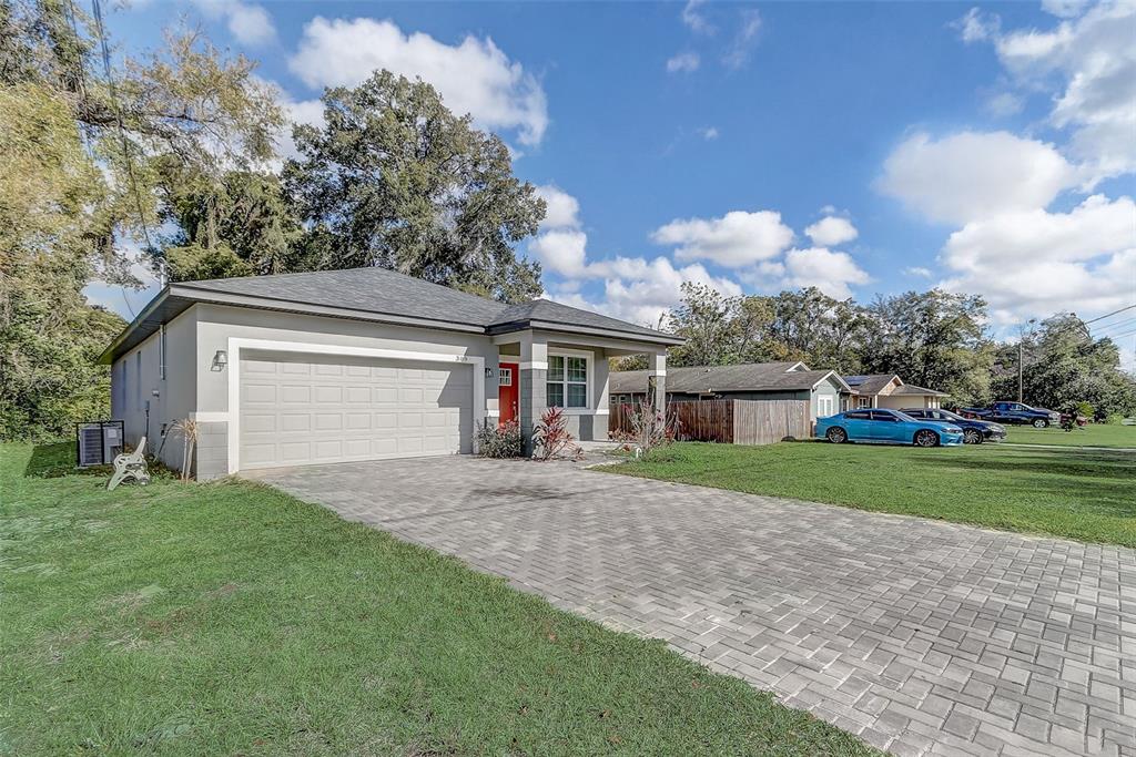 A single-story house with a paved driveway, a two-car garage, and a red front door — 309 E 13TH STREET, APOPKA, FL