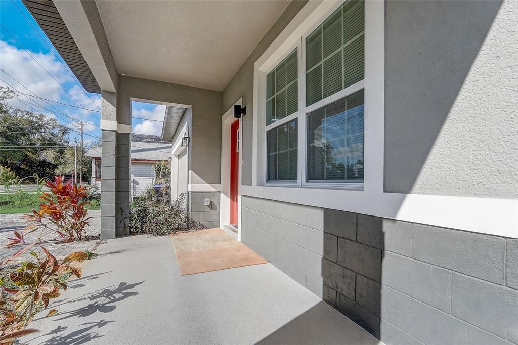 A covered front porch features a red door, gray concrete block walls, and a window — 309 E 13TH STREET, APOPKA, FL