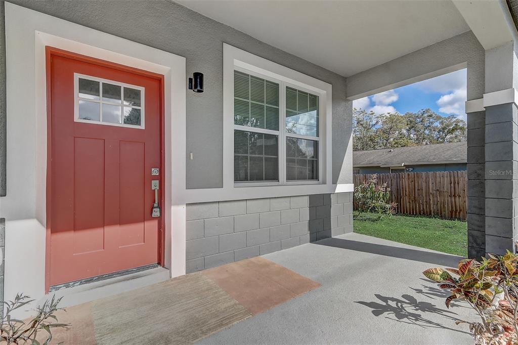 A covered front porch features a red door, a window, and gray concrete block siding — 309 E 13TH STREET, APOPKA, FL