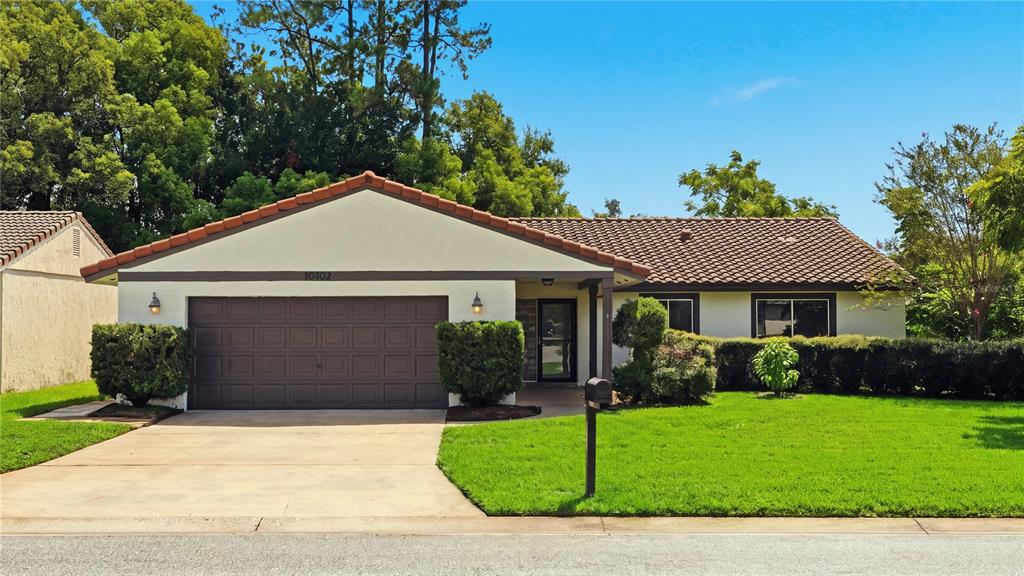A single-story house with a brown tile roof, a two-car garage, and a front lawn — 10702 WILLIAM TELL DRIVE, ORLANDO, FL