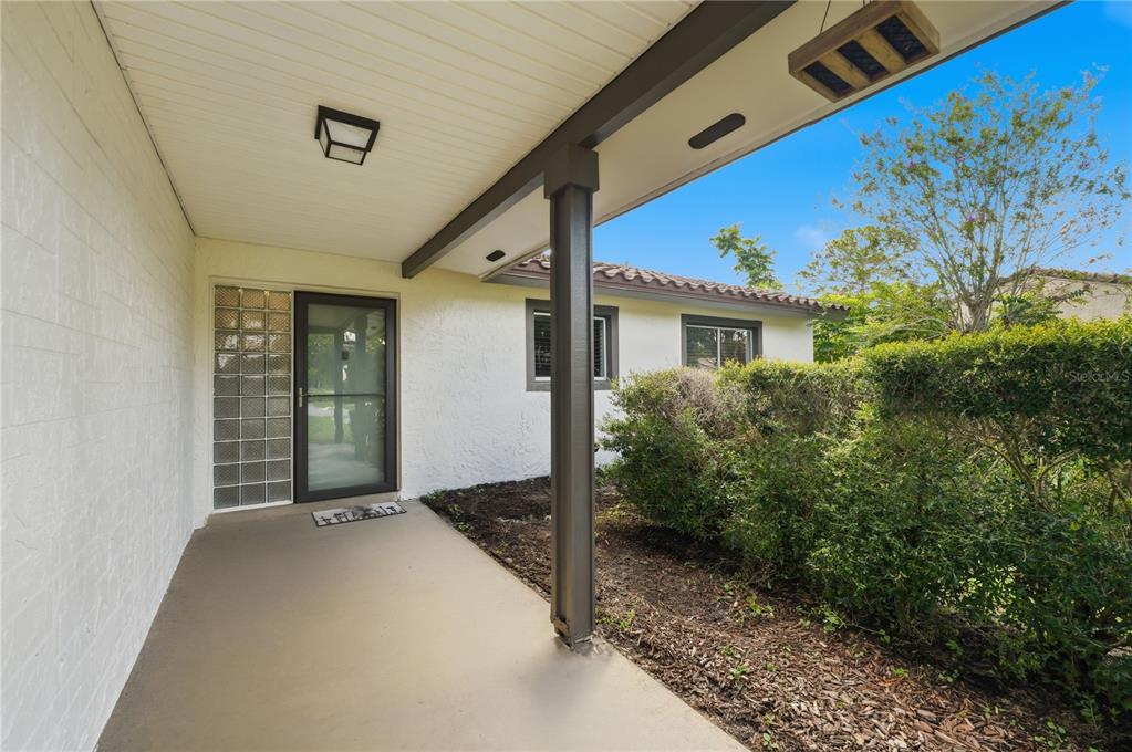 A covered concrete porch leads to a glass-paneled front door with a glass block sidelight — 10702 WILLIAM TELL DRIVE, ORLANDO, FL