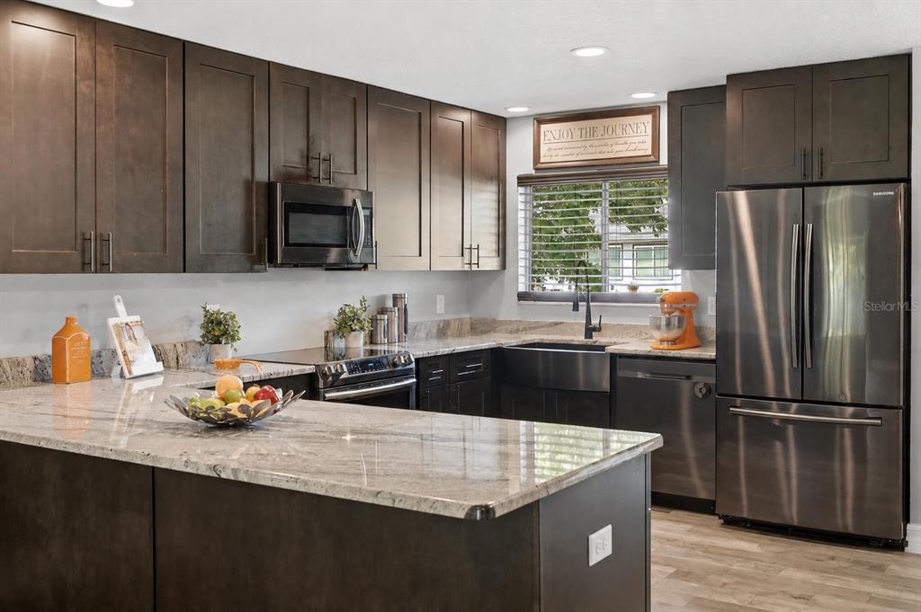 A kitchen features dark wood cabinets, granite countertops, stainless steel appliances, and a farmhouse sink — 10702 WILLIAM TELL DRIVE, ORLANDO, FL