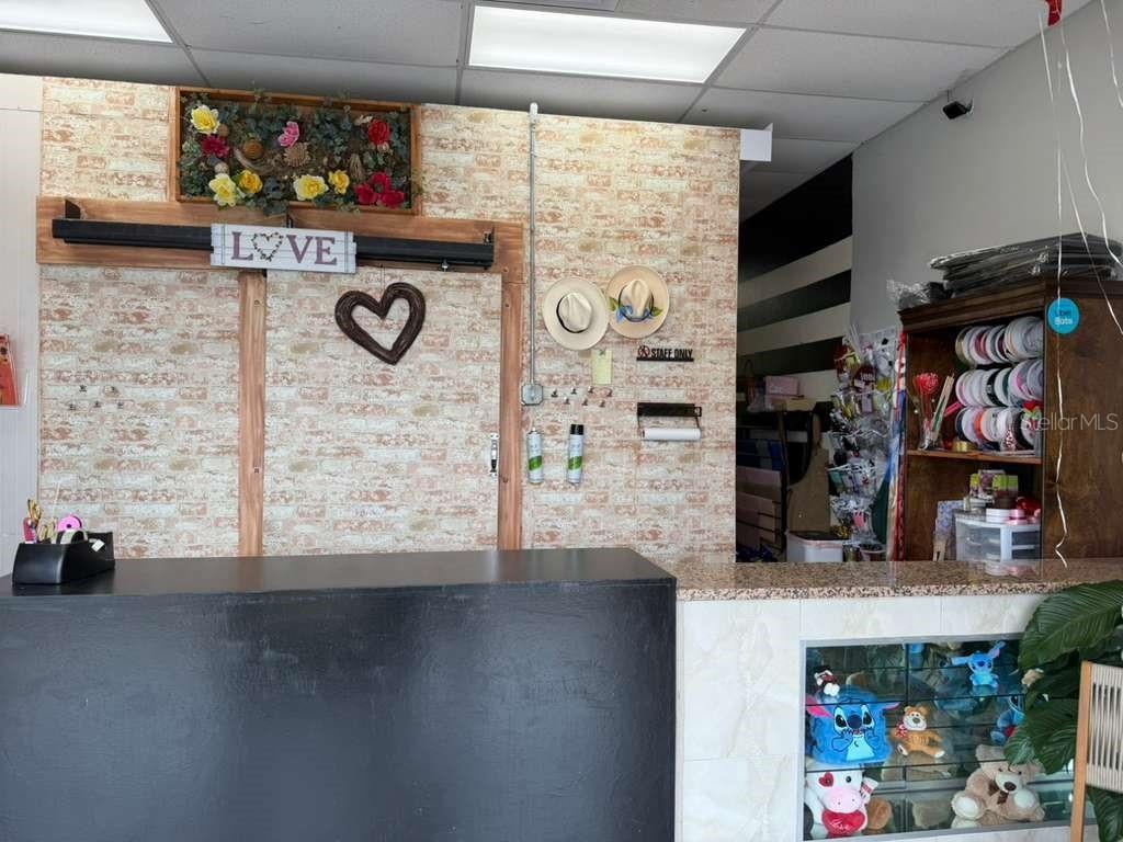 A retail counter stands in front of a brick-patterned wall decorated with a love sign — 7803 E COLONIAL DRIVE UNIT 106, ORLANDO, FL
