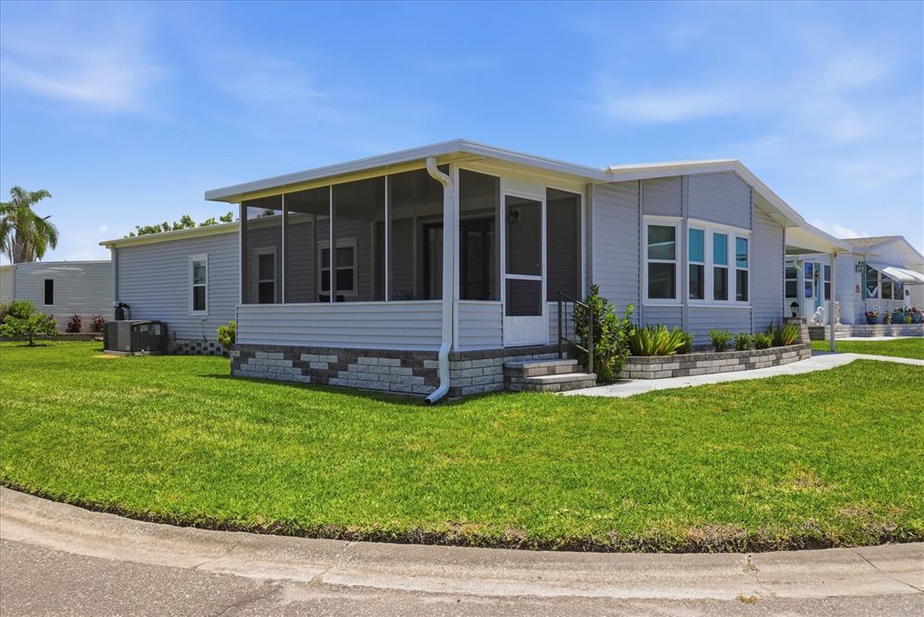 A light blue manufactured home features a screened-in front porch and a stone-patterned foundation — 1536 45TH AVENUE E, ELLENTON, FL