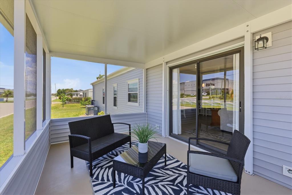 A screened-in porch features a black wicker seating set on a patterned rug — 1536 45TH AVENUE E, ELLENTON, FL