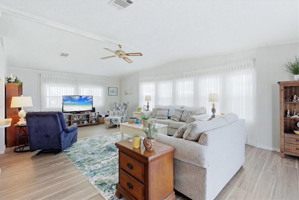 A living room features light wood-look flooring, a ceiling fan, and a large bay window — 1536 45TH AVENUE E, ELLENTON, FL