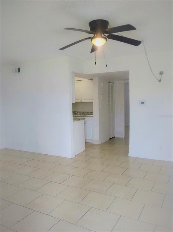 A room with white walls, light tile flooring, and a ceiling fan above — 302 S SPRING GARDEN AVENUE UNIT B09, DELAND, FL