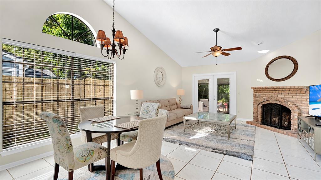 A living and dining area features tile floors, a brick fireplace, and vaulted ceilings — 2820 RISSER AVENUE, ORLANDO, FL