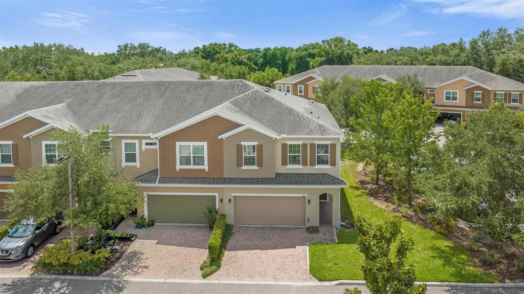 An aerial view shows a two-story townhouse with a paved driveway and attached garages — 1160 PALMA VERDE PLACE, APOPKA, FL