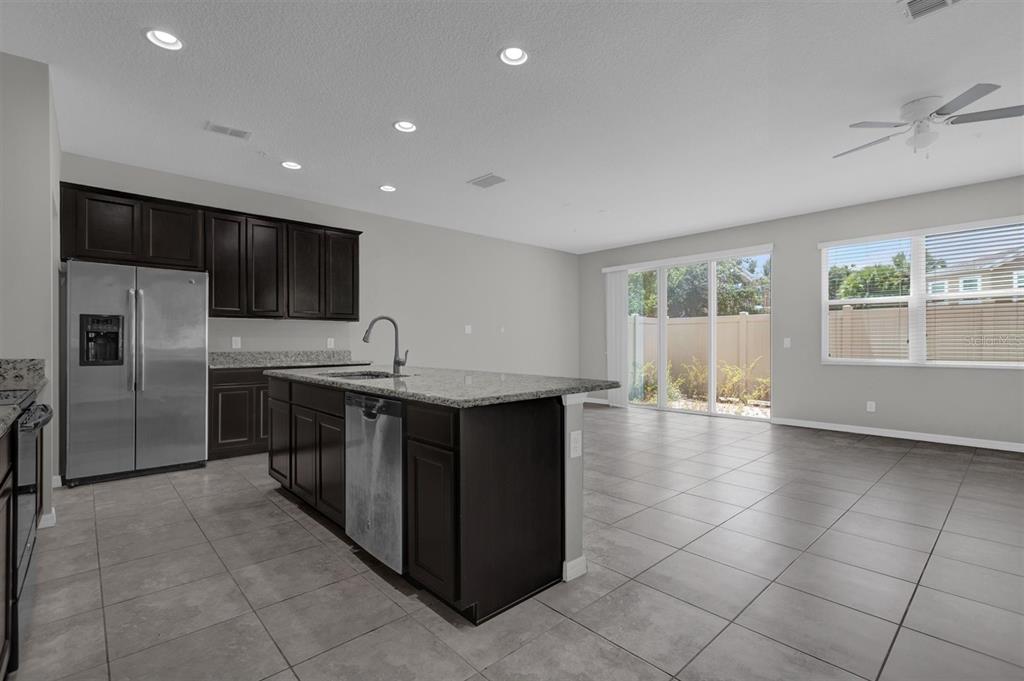 A kitchen with dark cabinets, granite countertops, stainless steel appliances, and tile flooring — 1160 PALMA VERDE PLACE, APOPKA, FL