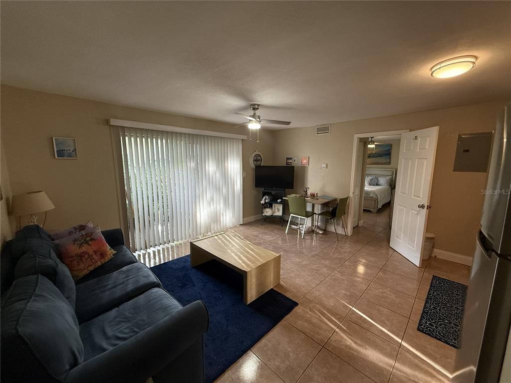 A living room features tile flooring, a blue sofa, a coffee table, and a dining area — 4215 E BAY DRIVE UNIT 1702B, CLEARWATER, FL