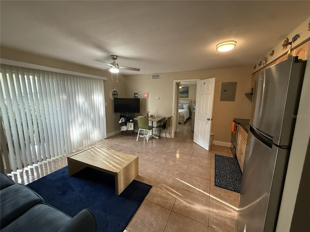 An open-concept living area features tile flooring, a kitchen, and a sliding glass door — 4215 E BAY DRIVE UNIT 1702B, CLEARWATER, FL