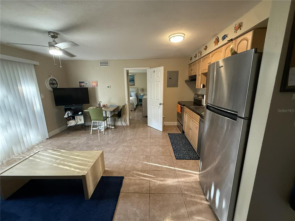 A kitchen with stainless steel appliances and tile flooring opens into a living area — 4215 E BAY DRIVE UNIT 1702B, CLEARWATER, FL