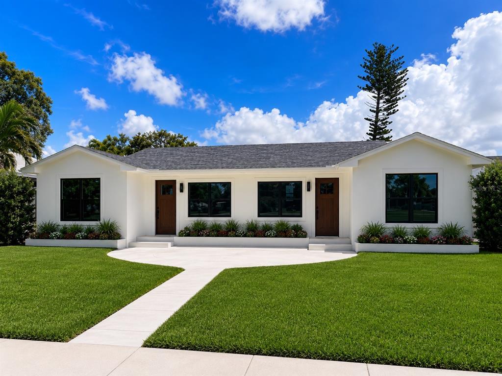 A white single-story house with two brown doors, black-framed windows, and a concrete front walkway — 3219 E DEBAZAN AVENUE, ST PETE BEACH, FL