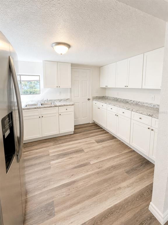A kitchen features white cabinets, granite countertops, and wood-look flooring — 1052 OSCEOLA TRAIL, CASSELBERRY, FL