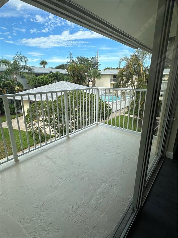 A balcony with white railings overlooks a swimming pool and surrounding apartment buildings — 809 HUMMINGBIRD WAY UNIT 5c, NORTH PALM BEACH, FL