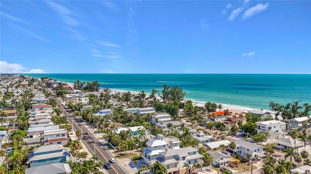 A three-story coastal house features a two-car garage, a white balcony, and light blue siding — 2918 GULF DRIVE, HOLMES BEACH, FL