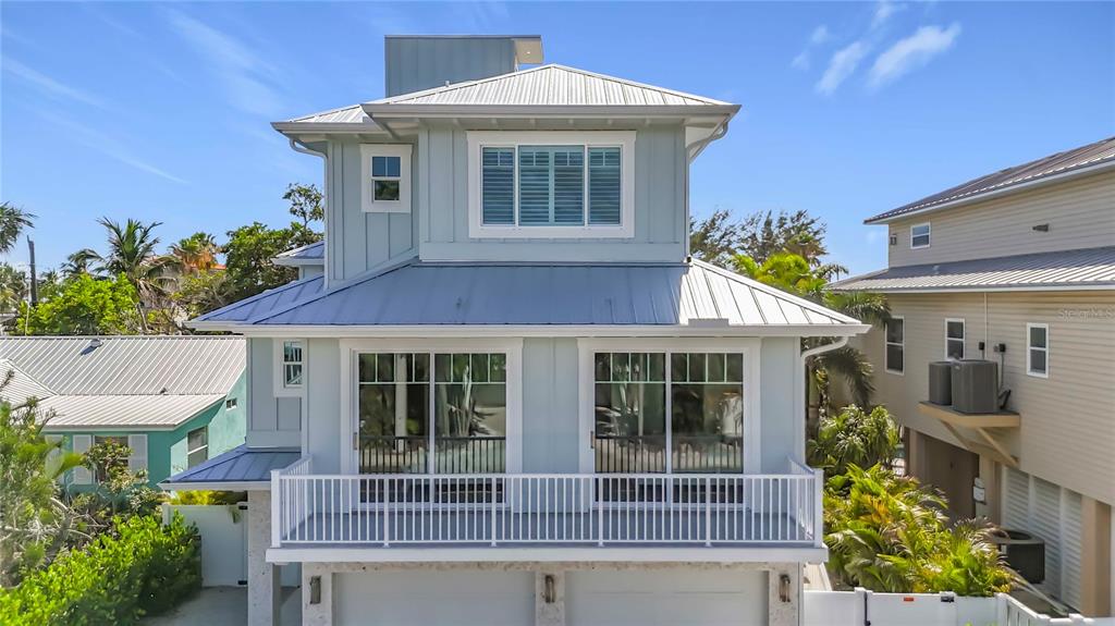 A three-story light blue house with a metal roof and a second-floor balcony — 2918 GULF DRIVE, HOLMES BEACH, FL