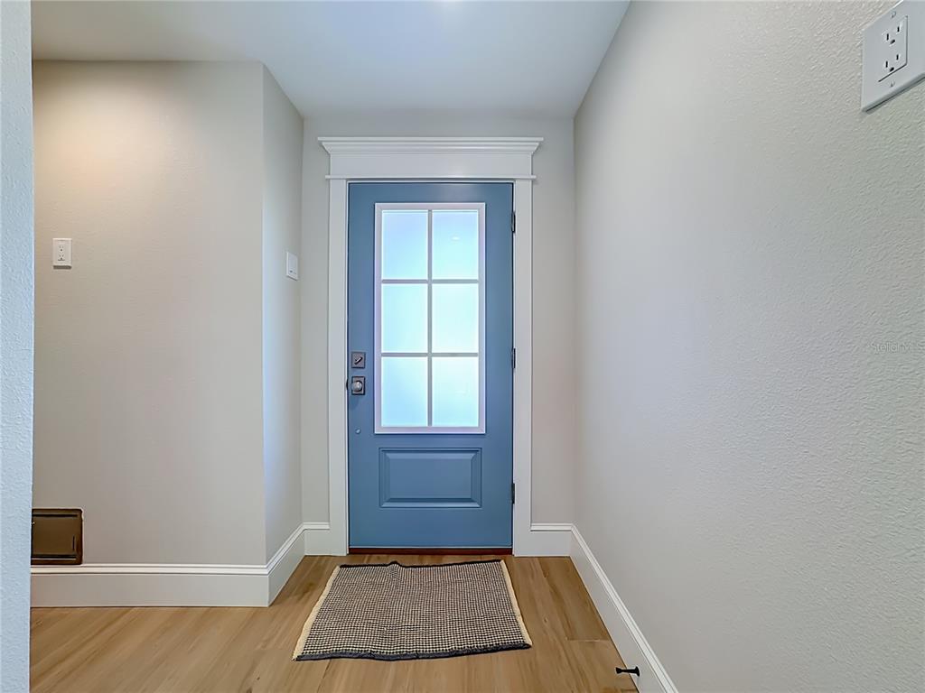 An entryway features a blue front door with a glass window and light wood flooring — 2918 GULF DRIVE, HOLMES BEACH, FL