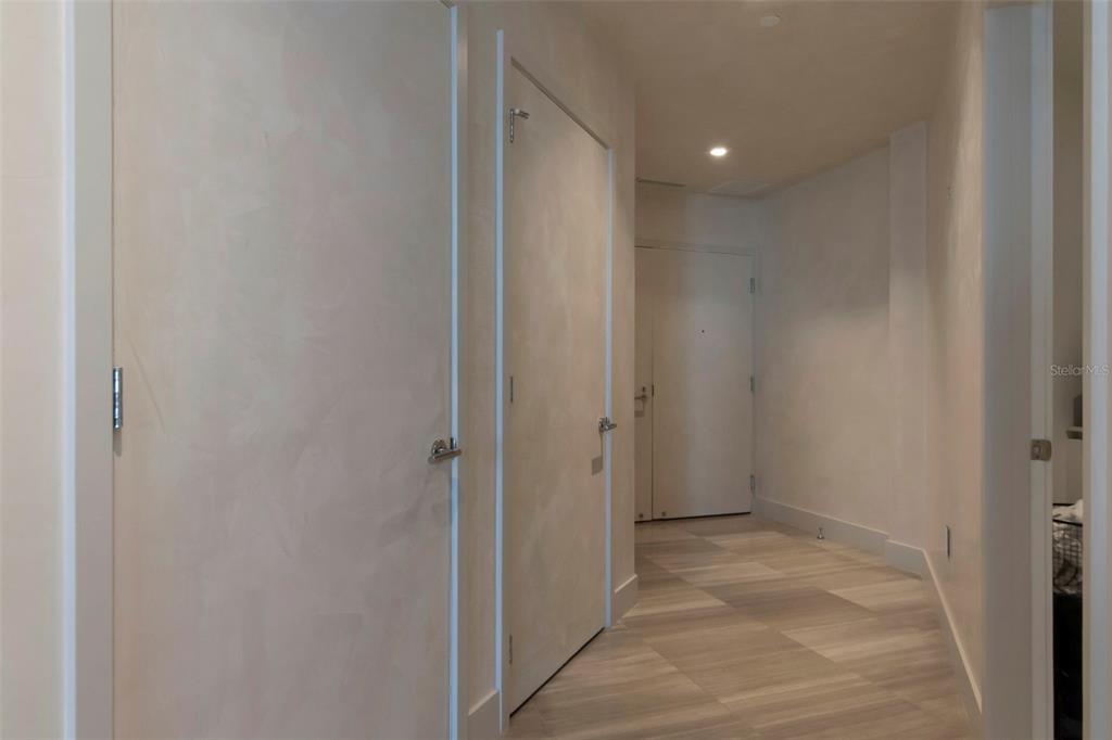 A hallway with light-colored walls, wood-look tile flooring, and several closed interior doors — 3101 BAYSHORE BOULEVARD UNIT 1001, TAMPA, FL