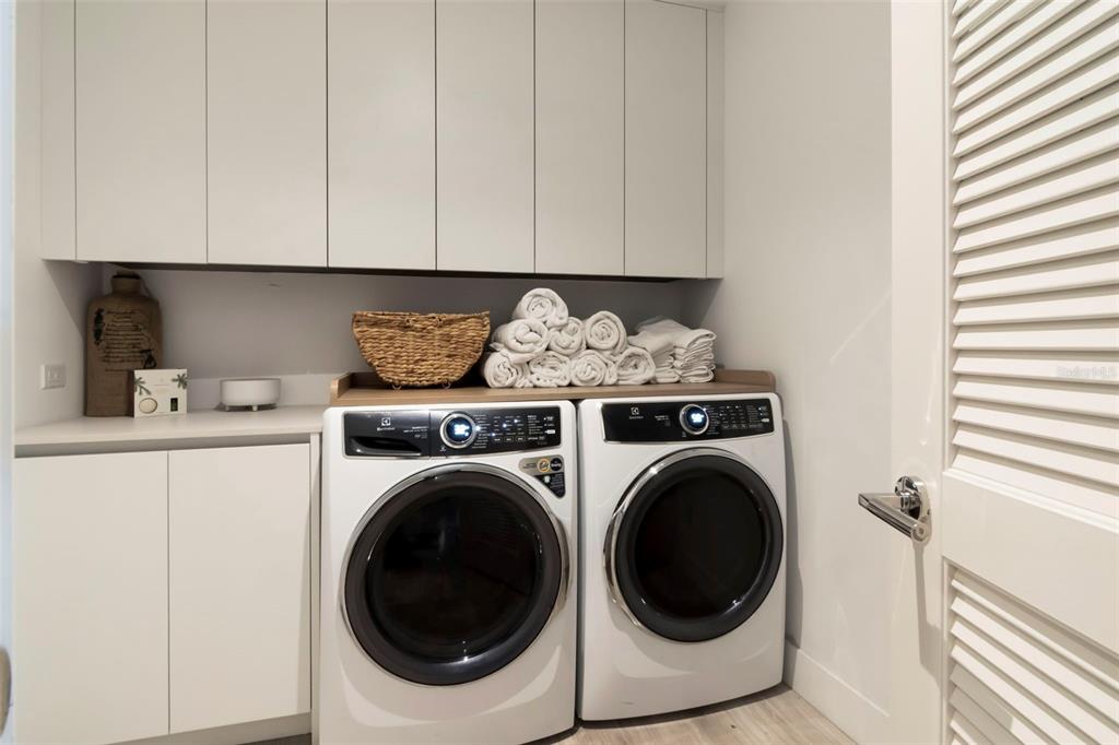 A laundry room features white cabinets, a wooden countertop, and a side-by-side washer and dryer — 3101 BAYSHORE BOULEVARD UNIT 1001, TAMPA, FL