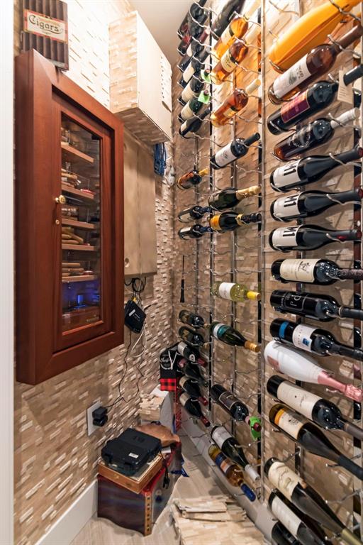 A small wine cellar features a wall-mounted humidor and metal wine racks on stone walls — 3101 BAYSHORE BOULEVARD UNIT 1001, TAMPA, FL