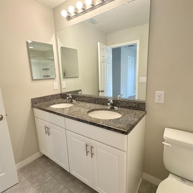 A bathroom features a double-sink vanity with a granite countertop and a large wall mirror — 7234 GRAND ELM DRIVE, RIVERVIEW, FL