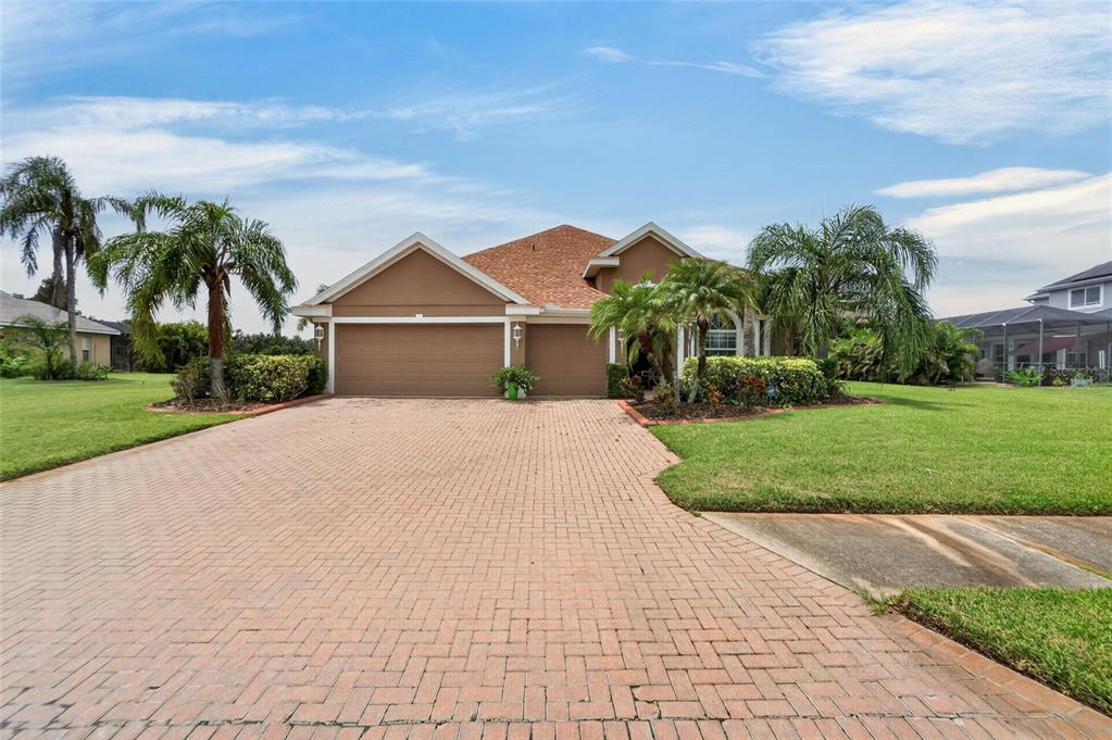 A tan single-story house with a brick paver driveway and palm trees in the front yard — 4315 70TH AVENUE E, ELLENTON, FL
