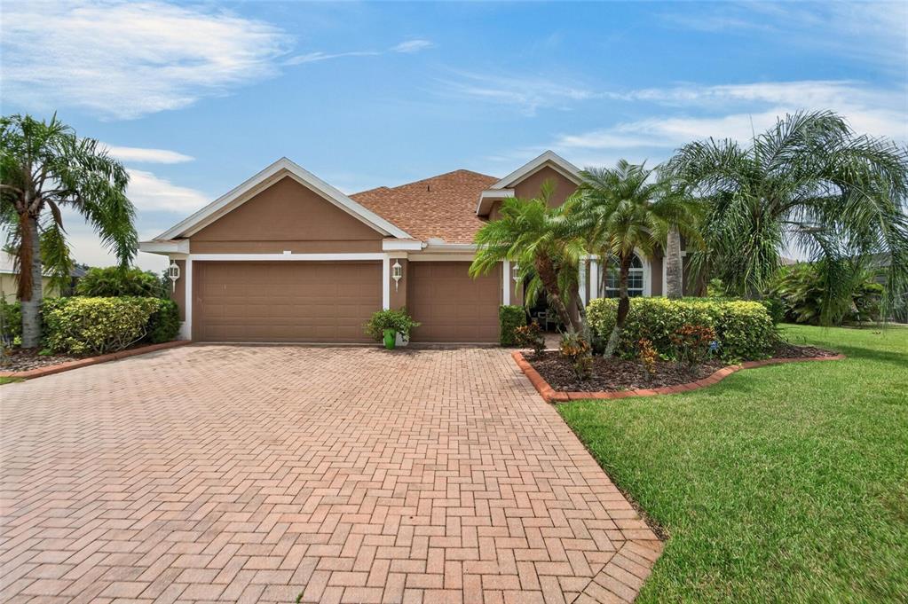 A single-story house with a brown exterior, a brick paver driveway, and palm trees — 4315 70TH AVENUE E, ELLENTON, FL