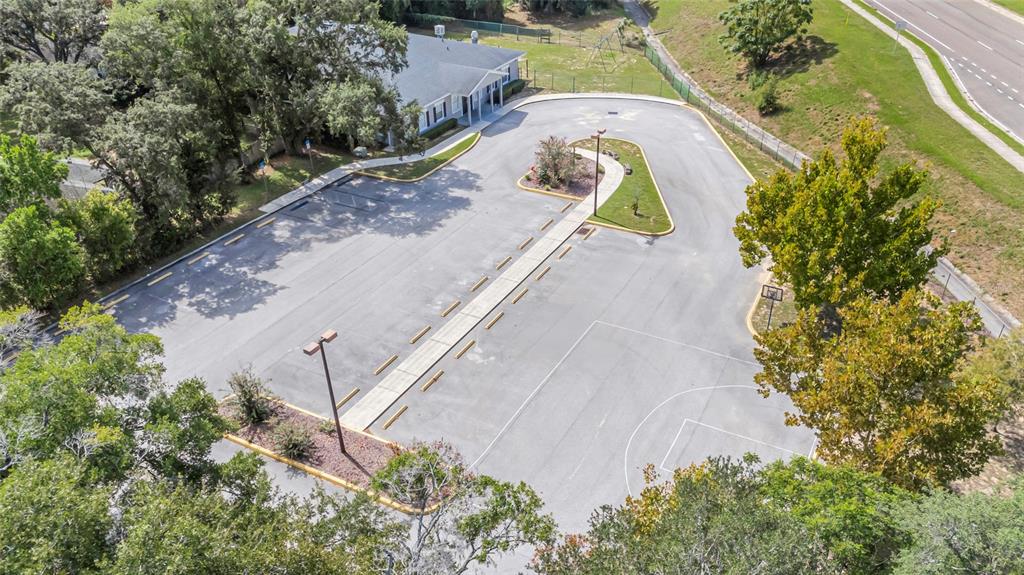 An aerial view shows a parking lot with a basketball court and a nearby building — 105 E BAKER STREET, MINNEOLA, FL