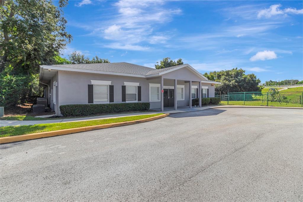 A single-story gray commercial building with a covered entrance and a paved parking lot — 105 E BAKER STREET, MINNEOLA, FL