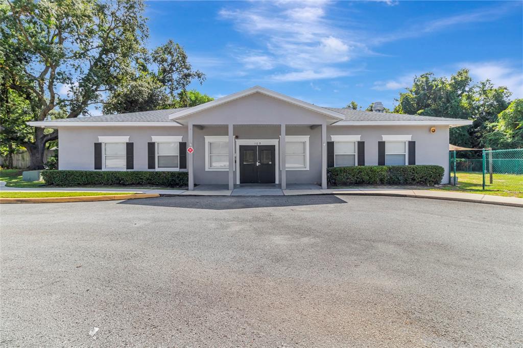 A single-story gray building with a covered entrance and black double doors — 105 E BAKER STREET, MINNEOLA, FL