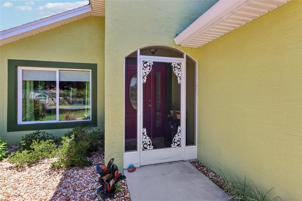 A lime green house exterior features a white storm door and a dark purple front door — 76 FAIRWAY CIRCLE, UMATILLA, FL