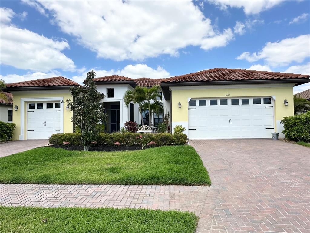 A single-story house with a tile roof, yellow stucco, and two white garage doors — 1802 5TH STREET E, PALMETTO, FL