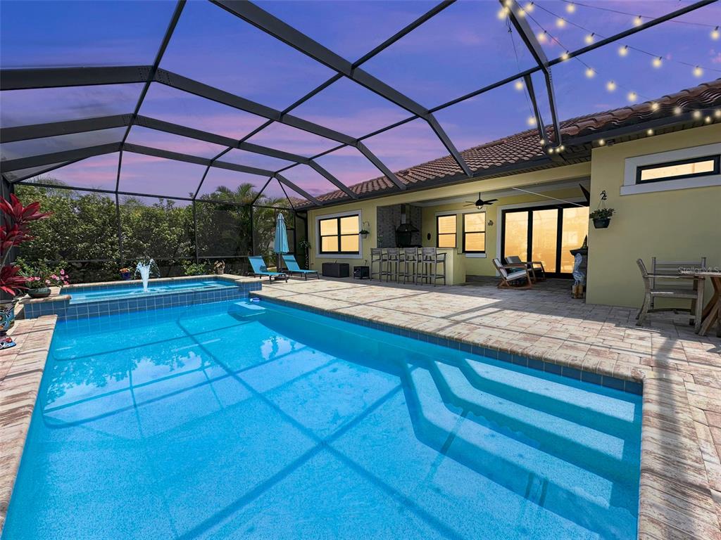 A screened-in patio features a swimming pool, a hot tub, and an outdoor kitchen area — 1802 5TH STREET E, PALMETTO, FL