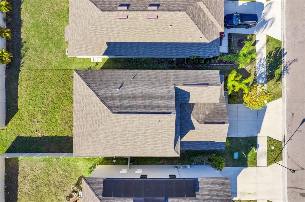 An aerial view shows the roofs of three suburban houses with driveways and grassy yards — 5204 WHITE CHICORY DRIVE, APOLLO BEACH, FL