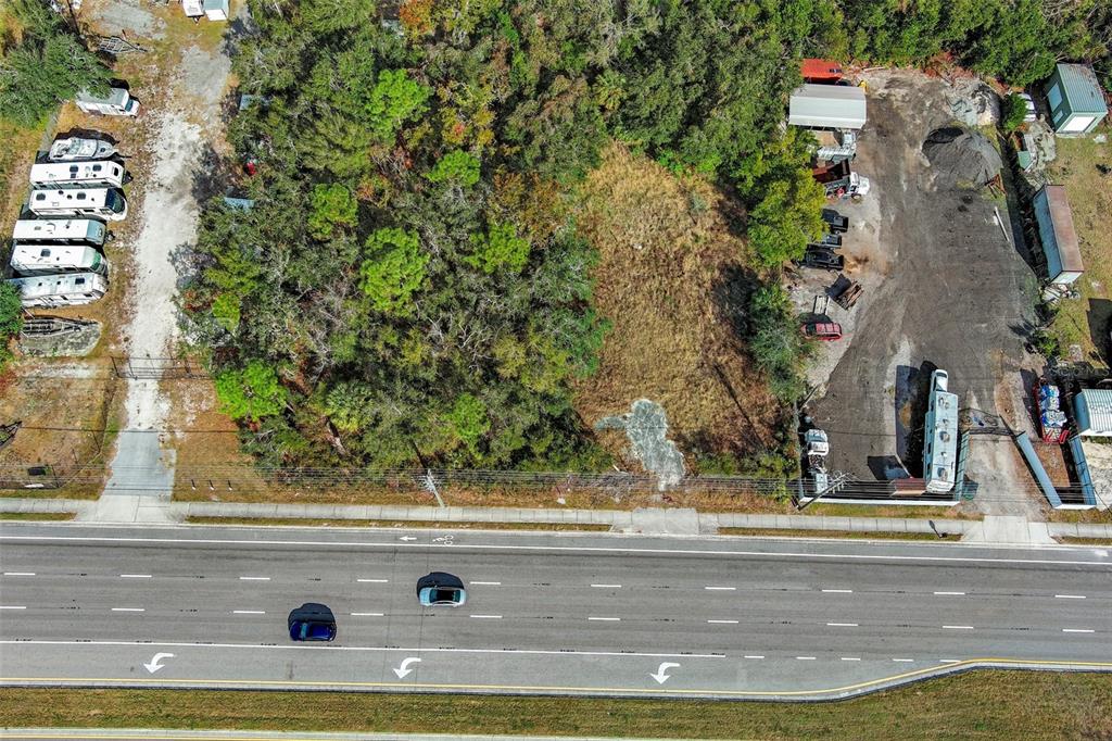 An aerial view shows a vacant lot situated between a storage area and a road — 10331 STATE ROAD 52, HUDSON, FL