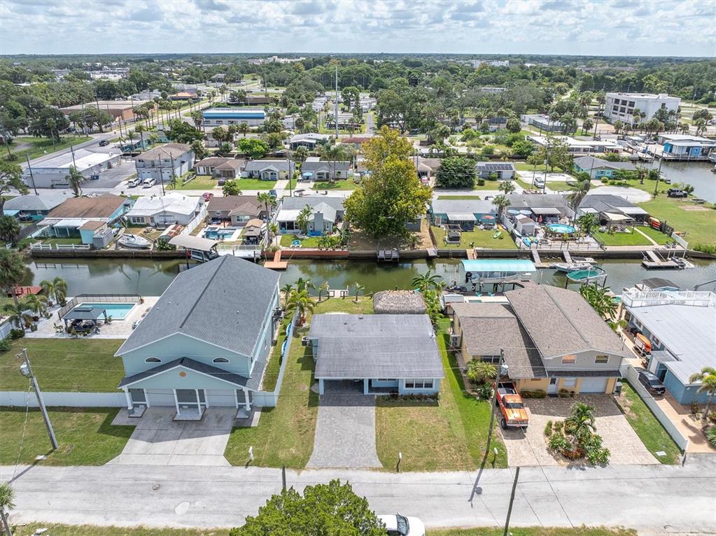 An aerial view shows three waterfront houses with private docks along a narrow canal — 13912 DULEY AVENUE, HUDSON, FL