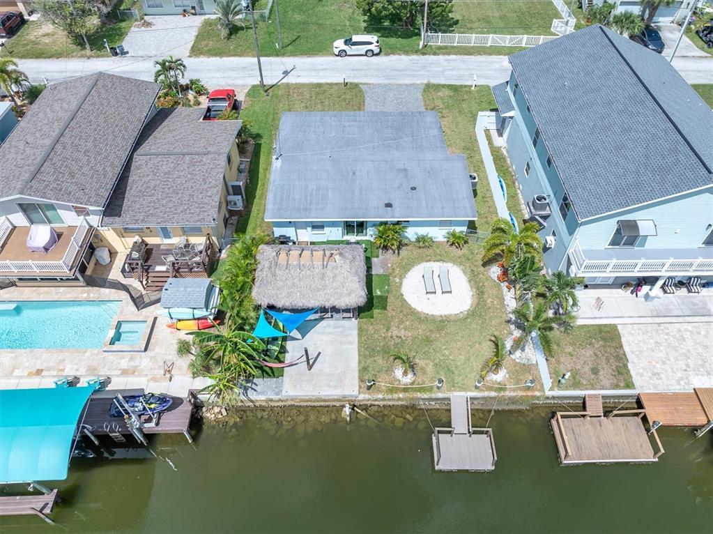 An aerial view shows three waterfront houses with docks, pools, and a tiki hut — 13912 DULEY AVENUE, HUDSON, FL