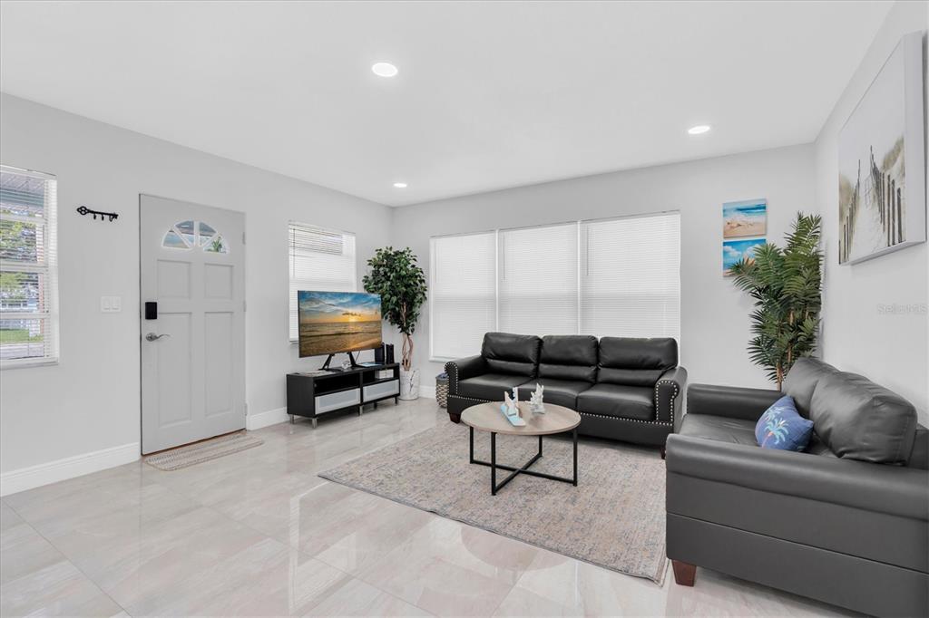 A living room features light tile floors, a black leather sofa, and a television console — 13912 DULEY AVENUE, HUDSON, FL
