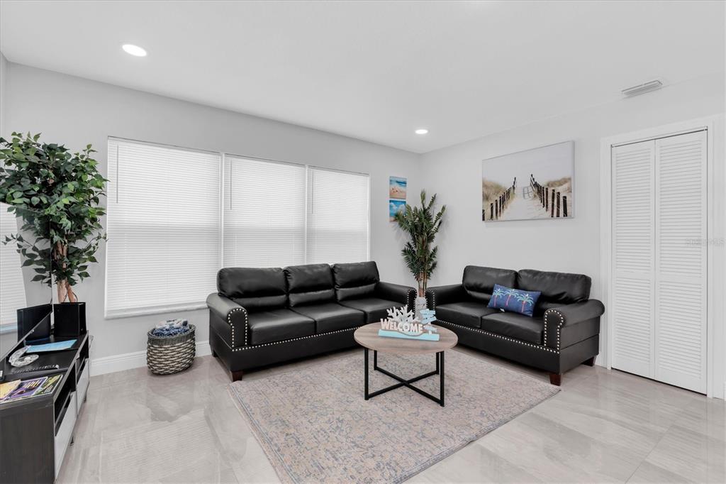 A living room features black leather sofas, a round coffee table, and light tile flooring — 13912 DULEY AVENUE, HUDSON, FL